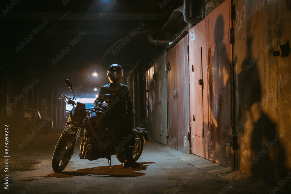 Portrait of a man in an outfit with a helmet and a motorcycle in a dark tunnel. Portrait of a man in an outfit with a helmet and a motorcycle in a dark tunnel.