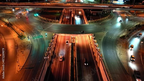 Financial technology, energy power, beautiful top view time-lapse of car traffic at roundabout lane and buildings. 4K drone aerial zoom out. Urban cityscape concept or abstract of advanced innovation.