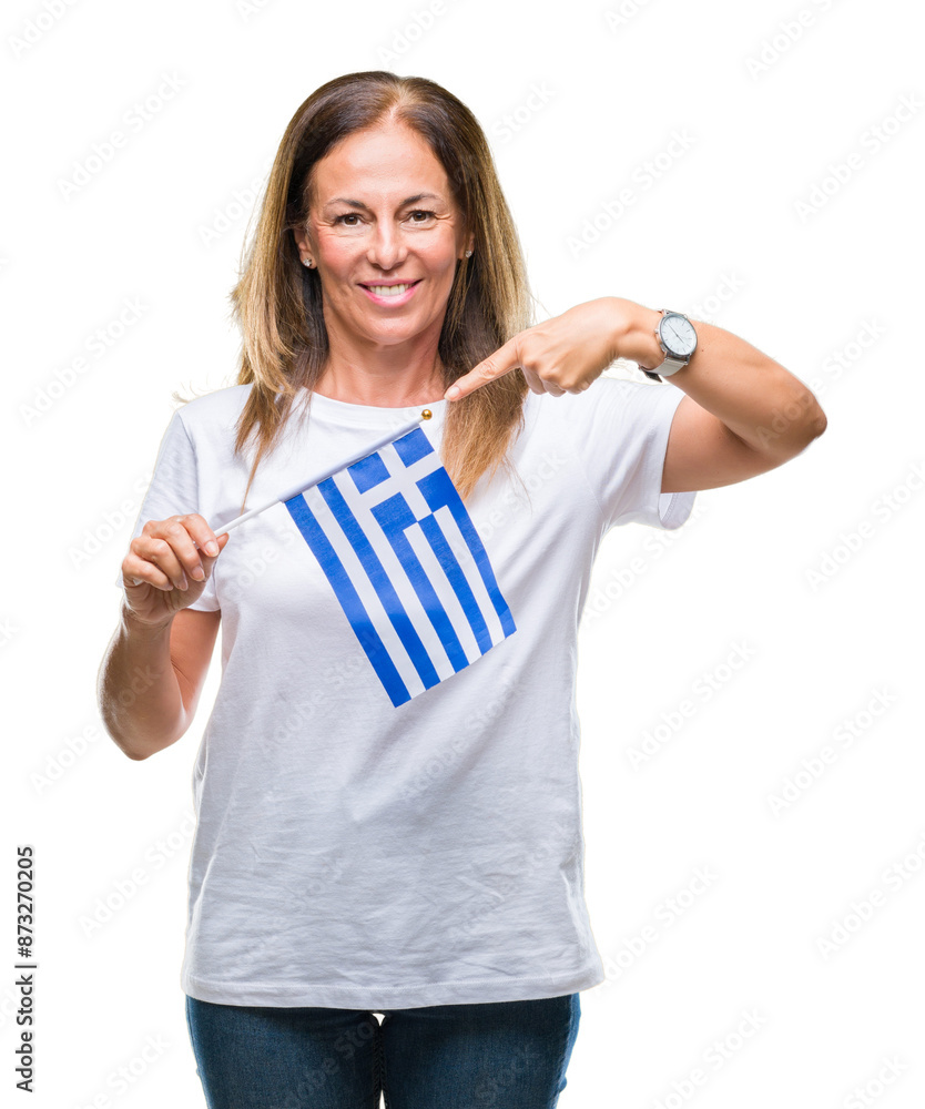 Middle age hispanic woman holding flag of Greece over isolated background very happy pointing with hand and finger Middle age hispanic woman holding flag of Greece over isolated background very happy pointing with hand and finger