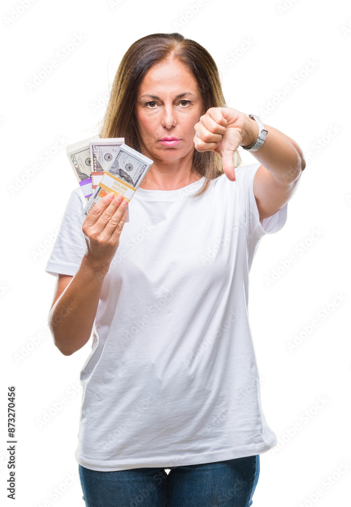Middle age hispanic woman holding bunch of dollars over isolated background with angry face, negative sign showing dislike with thumbs down, rejection concept Middle age hispanic woman holding bunch of dollars over isolated background with angry face, negative sign showing dislike with thumbs down, rejection concept