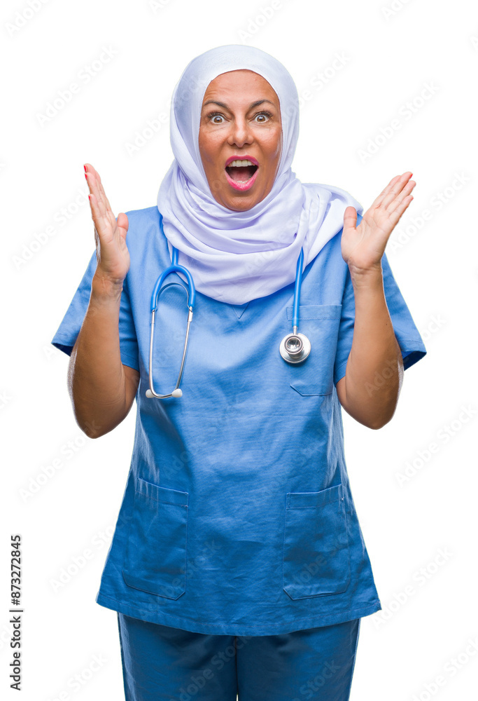 Middle age senior arab nurse woman wearing hijab over isolated background celebrating mad and crazy for success with arms raised and closed eyes screaming excited. Winner concept Middle age senior arab nurse woman wearing hijab over isolated background celebrating mad and crazy for success with arms raised and closed eyes screaming excited. Winner concept