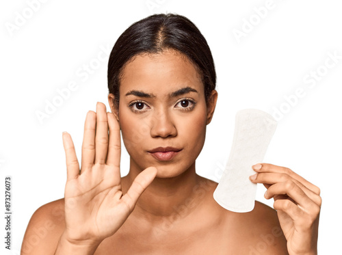 Filipino woman with sanitary pad in studio standing with outstretched hand showing stop sign, preventing you. photo