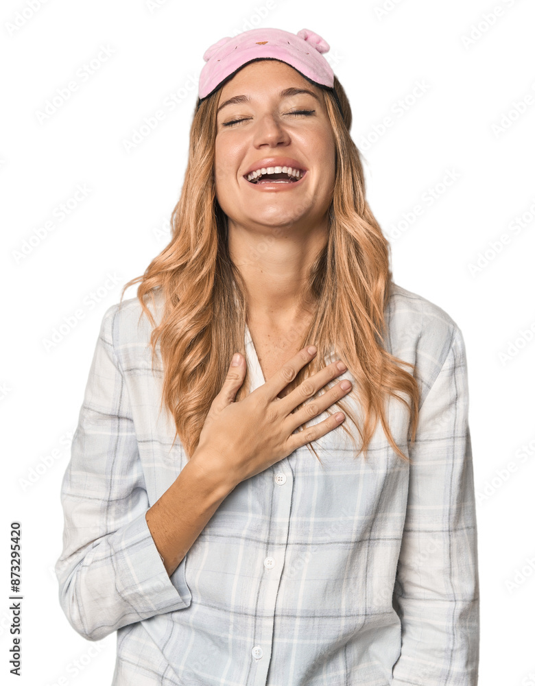Blonde in pajamas with sleep mask laughs out loudly keeping hand on chest. Blonde in pajamas with sleep mask laughs out loudly keeping hand on chest.