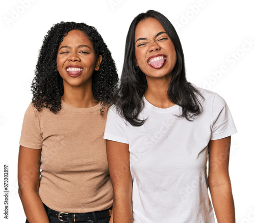 Young Latin friends in studio funny and friendly sticking out tongue.