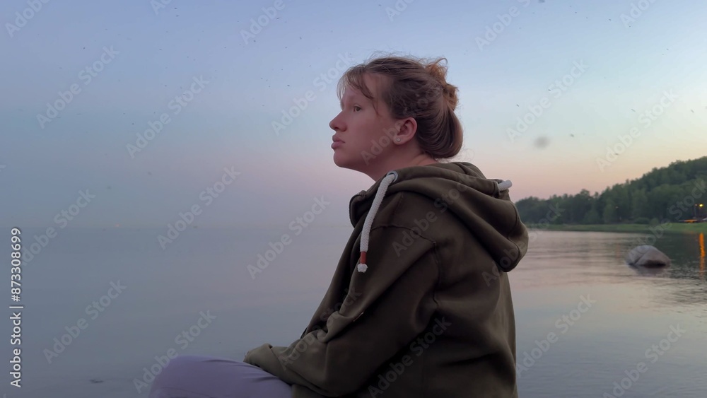 Young depressed sad woman sitting on the beach in the evening Young depressed sad woman sitting on the beach in the evening