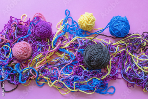 Tangled threads and an attempt to wind them into balls. Pink background, flat lay, copy space