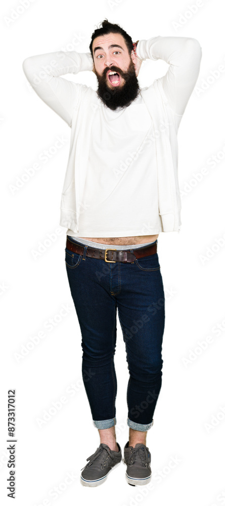 Young hipster man with long hair and beard wearing sporty sweatshirt Crazy and scared with hands on head, afraid and surprised of shock with open mouth Young hipster man with long hair and beard wearing sporty sweatshirt Crazy and scared with hands on head, afraid and surprised of shock with open mouth