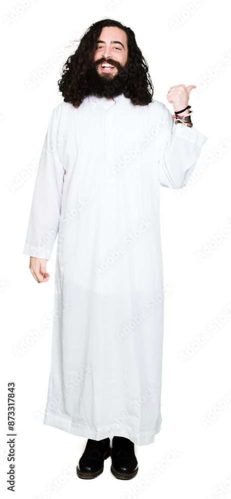 Man wearing Jesus Christ costume smiling with happy face looking and pointing to the side with thumb up. Man wearing Jesus Christ costume smiling with happy face looking and pointing to the side with thumb up.
