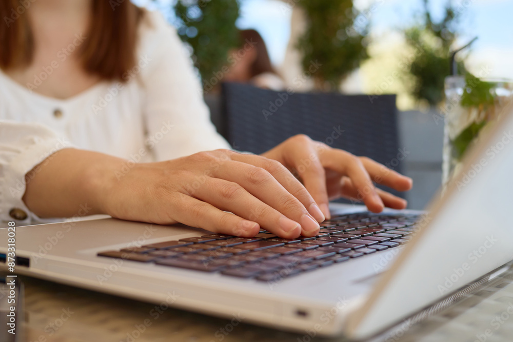 Fototapeta premium Unknown woman freelancer wearing white elegant dress combines her vacation and remote job working on portable computer using wireless wifi internet typing on laptop keyboard
