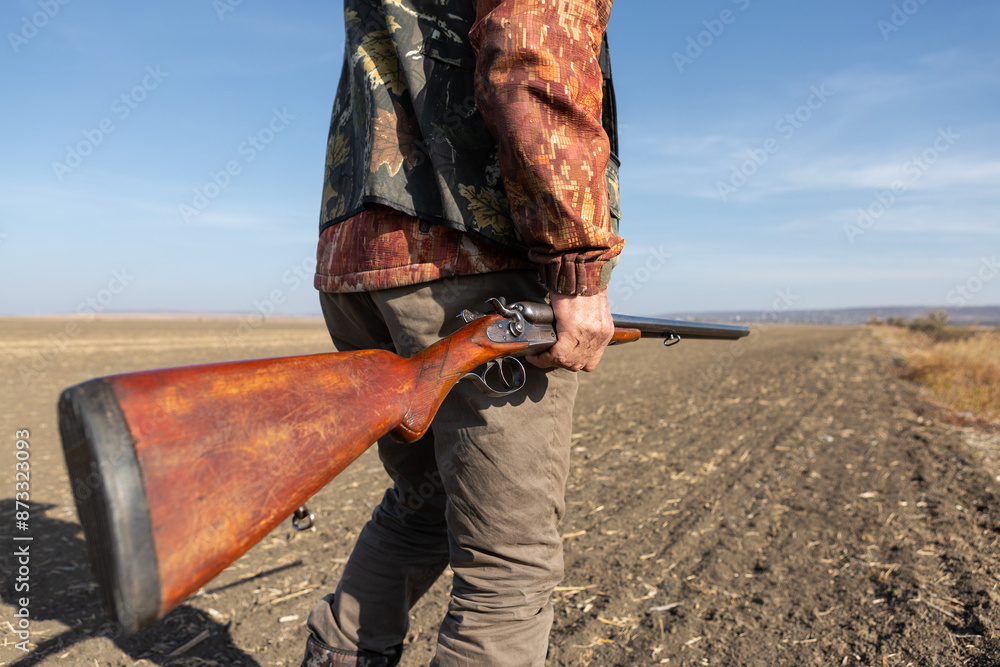 Mature man hunter with gun while walking on field. Mature man hunter with gun while walking on field.