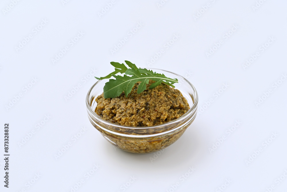 green olive and arugula tapenade in a bowl on a white background close-up