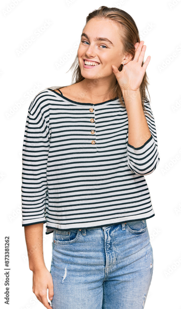 Beautiful blonde woman wearing casual clothes smiling with hand over ear listening an hearing to rumor or gossip. deafness concept. Beautiful blonde woman wearing casual clothes smiling with hand over ear listening an hearing to rumor or gossip. deafness concept.