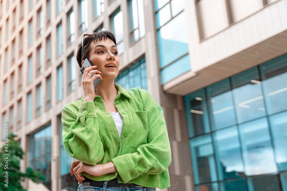 Woman in Green Shirt Talking on Phone in Urban Setting Woman in Green Shirt Talking on Phone in Urban Setting