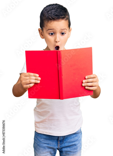 Little cute boy kid reading a book scared and amazed with open mouth for surprise, disbelief face photo