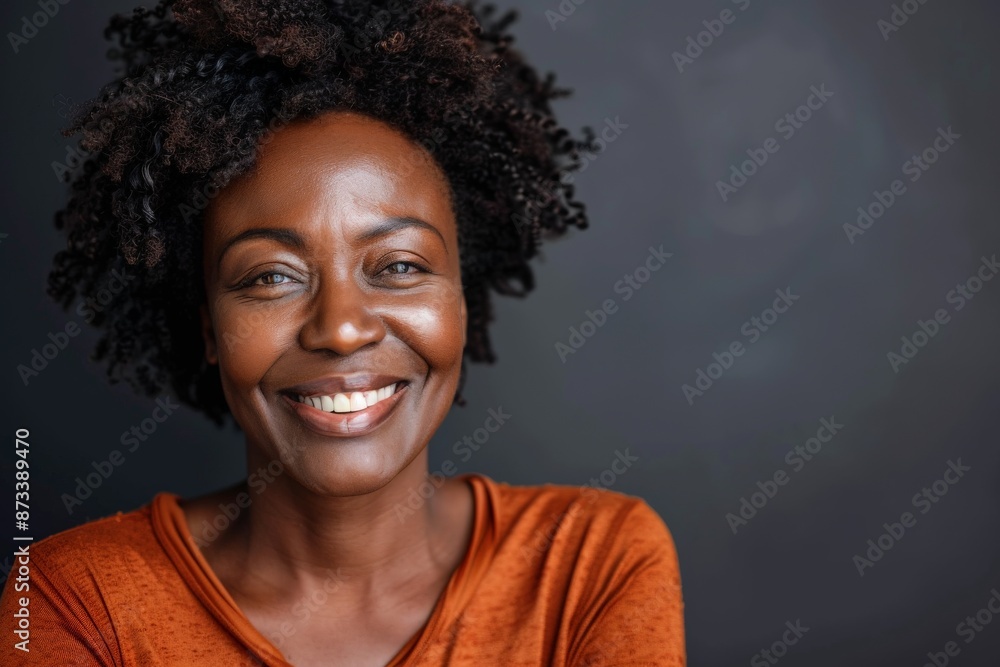 A happy woman dressed in an orange outfit is captured smiling radiantly, portrayed in a bright indoor setting, epitomizing warmth, positivity, and confidence. A happy woman dressed in an orange outfit is captured smiling radiantly, portrayed in a bright indoor setting, epitomizing warmth, positivity, and confidence.