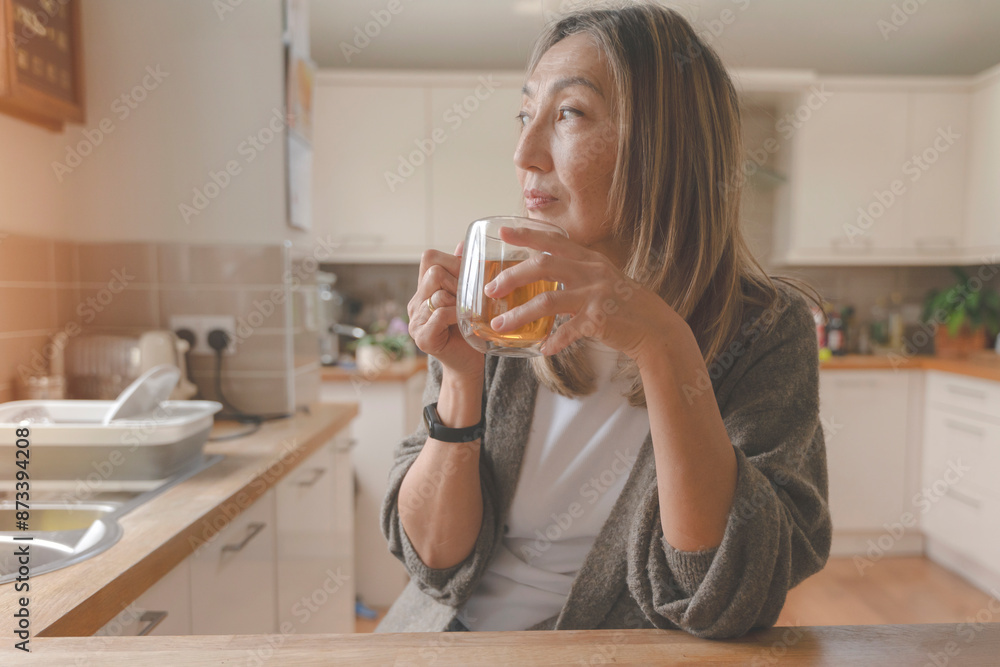 Woman Drinks Tea While Looking Out Kitchen Window Woman Drinks Tea While Looking Out Kitchen Window