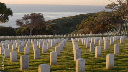 Rows of gravestones at Fort Rosecrans National Cemetery  in San Diego California during sunset with views of the skyline and Pacific Ocean over the horizon