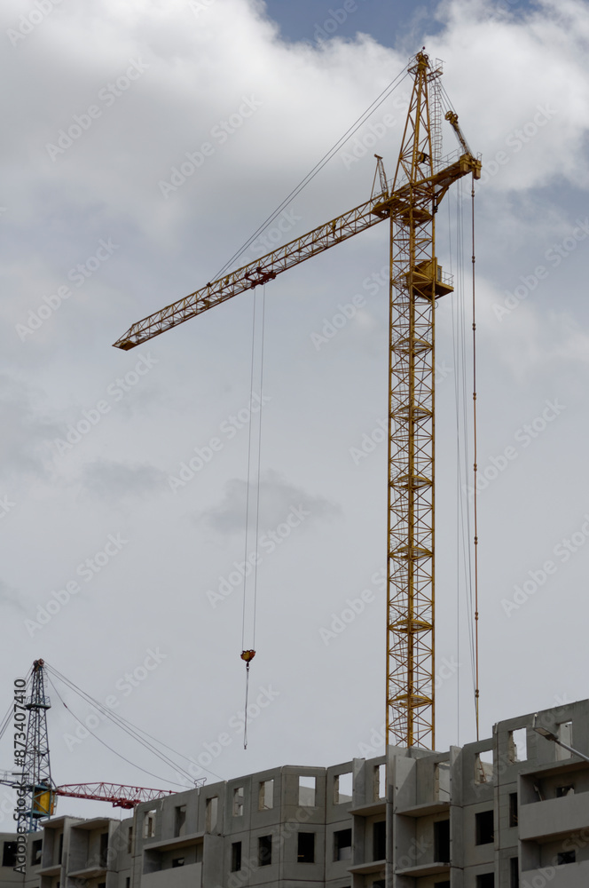 view of a residential complex under construction against the backdrop of a construction crane, standard condos for the middle class, housing concept view of a residential complex under construction against the backdrop of a construction crane, standard condos for the middle class, housing concept