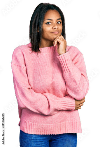 Beautiful hispanic woman wearing casual winter sweater with hand on chin thinking about question, pensive expression. smiling with thoughtful face. doubt concept.