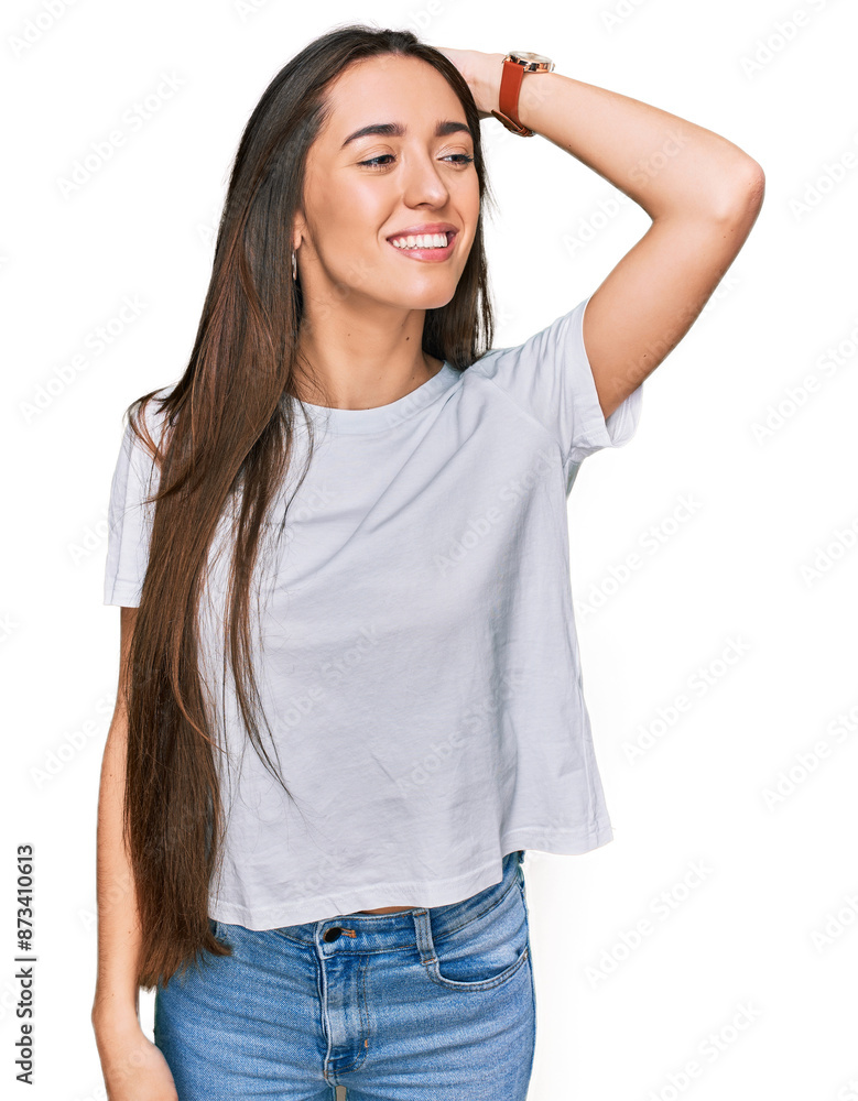 Fototapeta premium Young hispanic girl wearing casual white t shirt smiling confident touching hair with hand up gesture, posing attractive and fashionable
