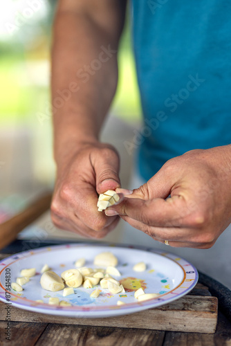 Cutting fresh garlic in hand with a knife. Natural healthy food spices and ingredient and seasoning for cooking on plate