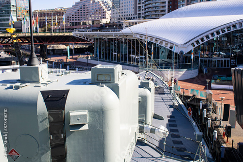 Capturing the majestic strength of an Australian naval warship in Sydney's sea, this strikingphoto features the formidable back of a cannon against the backdrop of Sydney's iconic cityscape.  photo