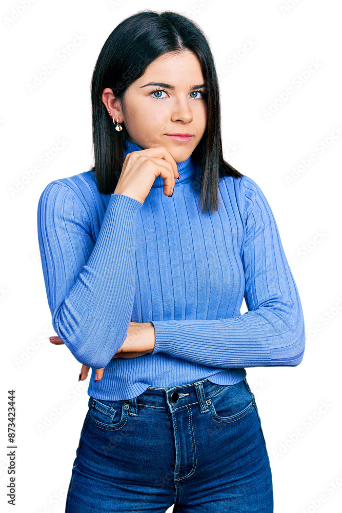 Young brunette woman with blue eyes wearing casual turtleneck sweater thinking concentrated about doubt with finger on chin and looking up wondering Young brunette woman with blue eyes wearing casual turtleneck sweater thinking concentrated about doubt with finger on chin and looking up wondering