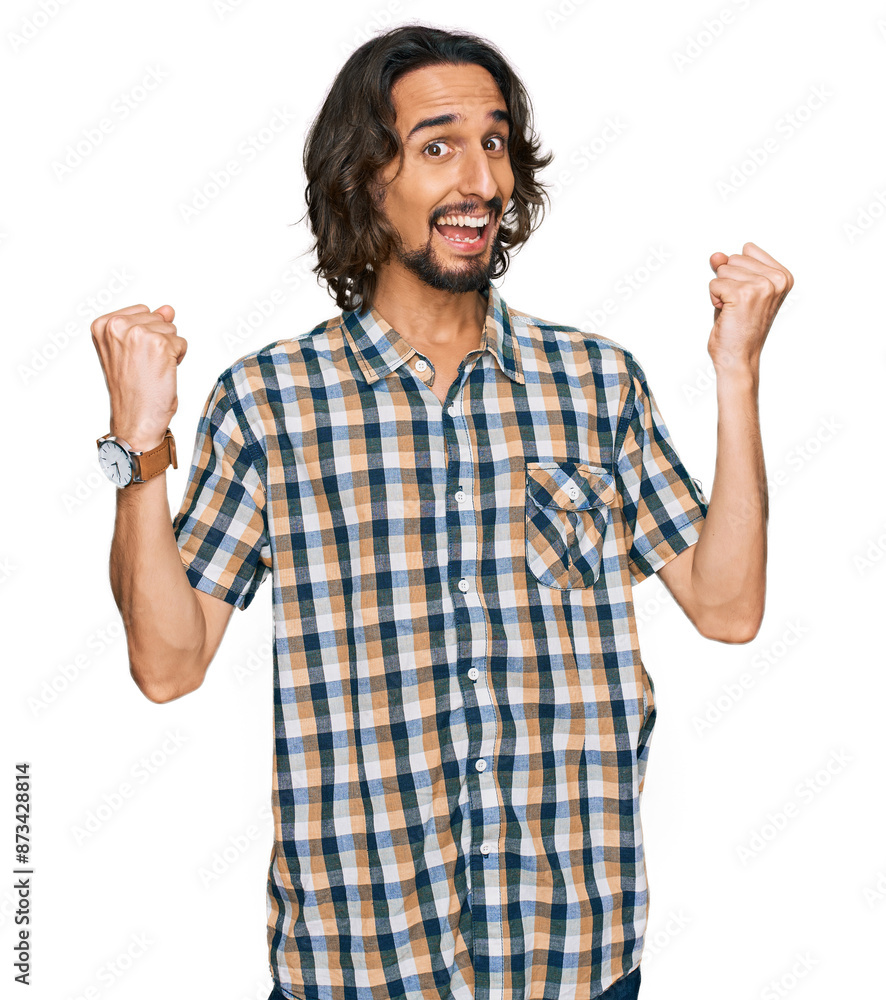 Young hispanic man wearing casual clothes screaming proud, celebrating victory and success very excited with raised arms Young hispanic man wearing casual clothes screaming proud, celebrating victory and success very excited with raised arms