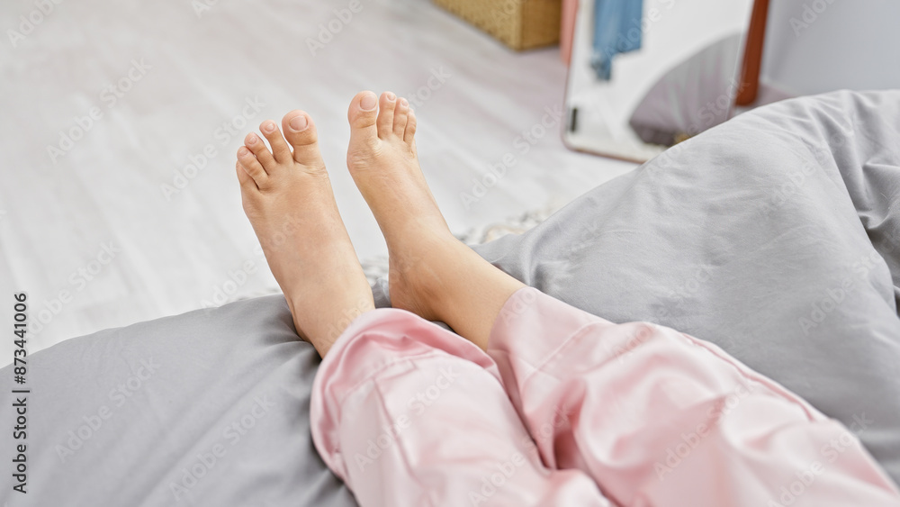 Close-up of bare feet in bed with pink pajamas showcasing relaxation in a cozy bedroom setting. Close-up of bare feet in bed with pink pajamas showcasing relaxation in a cozy bedroom setting.