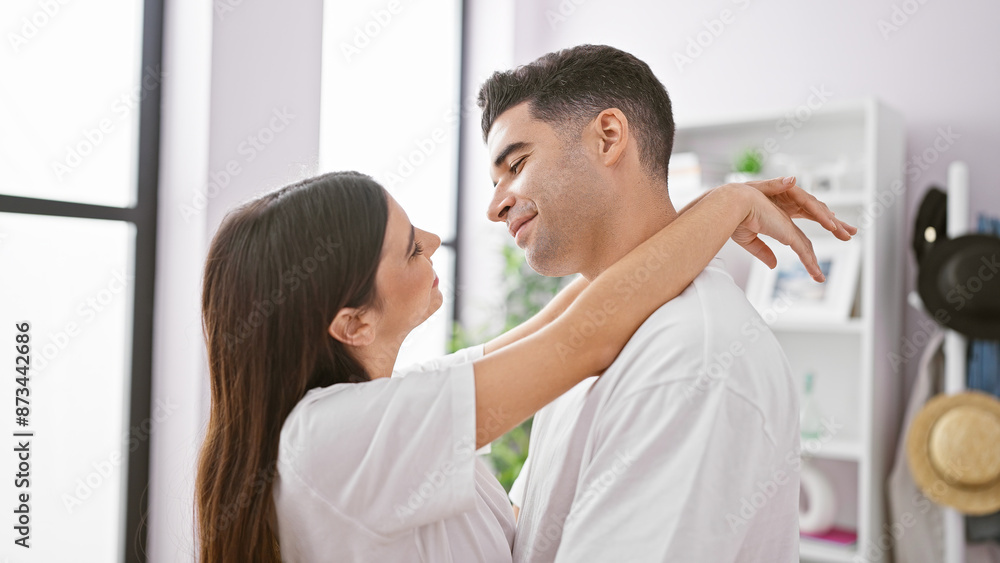 Fototapeta premium A man and a woman in a tender embrace at home, symbolizing love, family, and a harmonious relationship in a cozy living room setting.