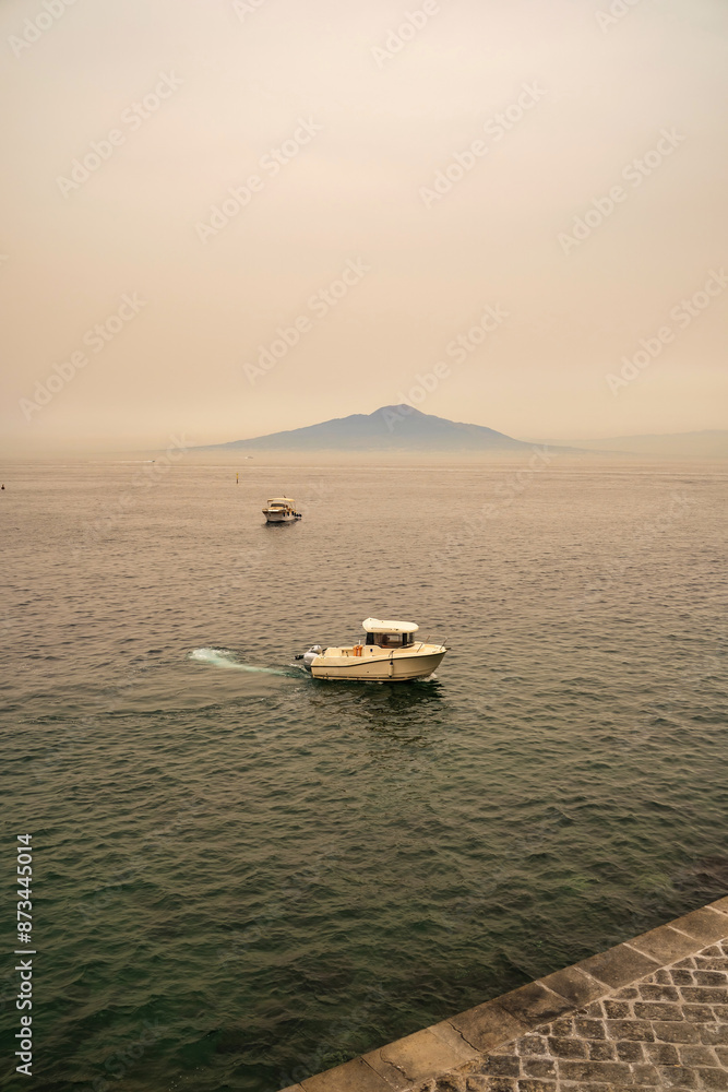 A motor boat sailing on a sea of Sorrento town in Italy against mount vesuvius volcano mount