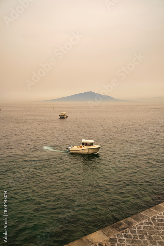 Obraz na płótnie A motor boat sailing on a sea of Sorrento town in Italy against mount vesuvius volcano mount w salonie