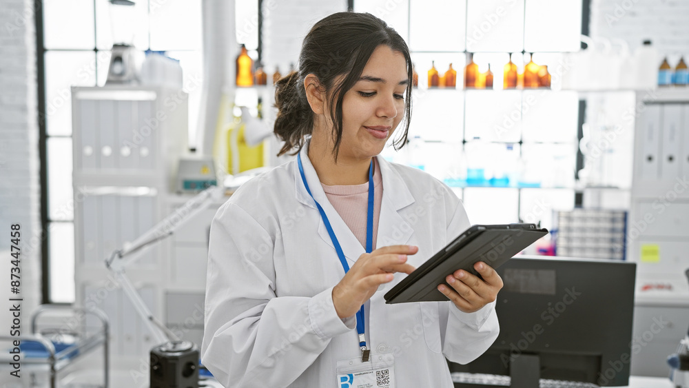 Hispanic woman scientist working with tablet in modern laboratory.