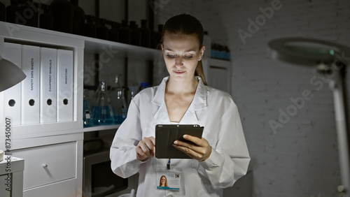 Focused young woman scientist using a tablet in a modern laboratory setting. photo