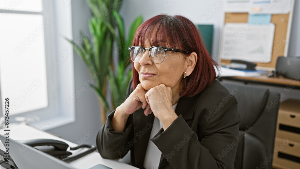 Pensive mature hispanic woman with glasses in a modern office setting. Pensive mature hispanic woman with glasses in a modern office setting.