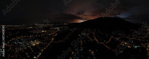 Atardecer en la ciudad de la furia, Quito - Ecuador, se ve de fondo el Pichincha desde San Antonio, norte de la ciudad. Atardecer con luces prendidas de las vías y casas, sol cayendo en el horizonte.