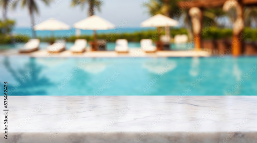 Naklejka premium Marble tabletop with empty space overlooking blurred resort pool, lounge chairs, and sun umbrellas for copy placement