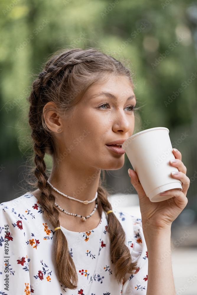 girl drinks coffee sitting at a table on a city street