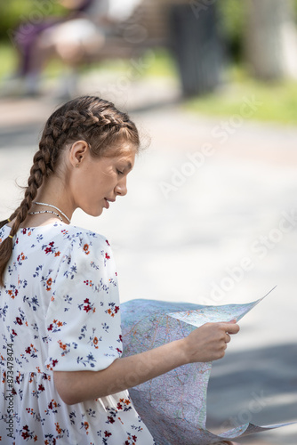 Woman hands with a city map sitting on a bench, travelling on a bright sunny day in city