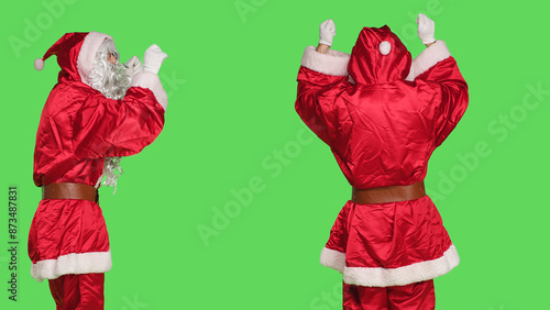 Saint nick musician conducting orchestra, choirmaster in costume accompany choir notes over greenscreen backdrop. Santa acting like musical director, musician singing in studio.