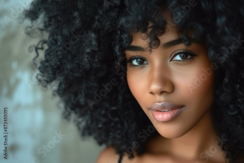 Close-up portrait of a beautiful young woman with voluminous curly hair and soft gaze