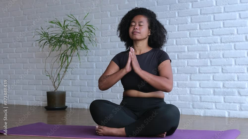 South Asian woman practicing meditation on mat at home. Calm meditation helps find inner balance. Regular meditation to relieving stress and improving well-being. Deep immersion in practice at house. South Asian woman practicing meditation on mat at home. Calm meditation helps find inner balance. Regular meditation to relieving stress and improving well-being. Deep immersion in practice at house.