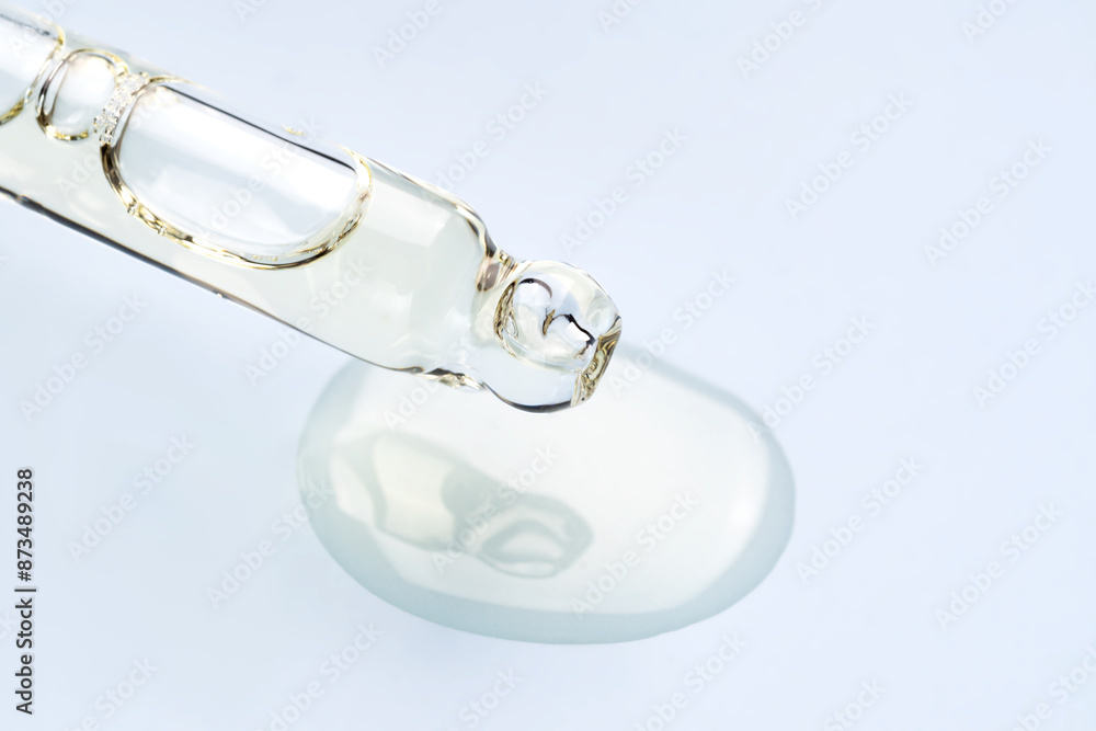 Close-up view of a cosmetic serum dropper on blue background Close-up view of a cosmetic serum dropper on blue background