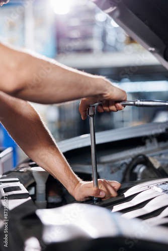 Close up shot of repairman in car service uses torque wrench to tighten bolts after replacing motor. Skilled auto repair shop worker uses professional tools to fix automobile © DC Studio