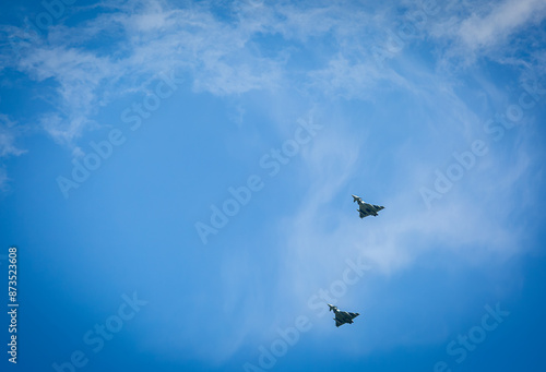 Two RAF typhoons flying, flying in formation back to their respected air fields after taking part in the kings fly past on a beautiful summers day with blue skies and slight cloud