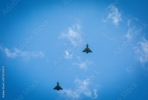 Two RAF typhoons flying, flying in formation back to their respected air fields after taking part in the kings fly past on a beautiful summers day with blue skies and slight cloud photo