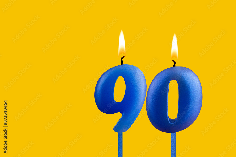 Blue birthday candle on yellow background - Number 90 Blue birthday candle on yellow background - Number 90