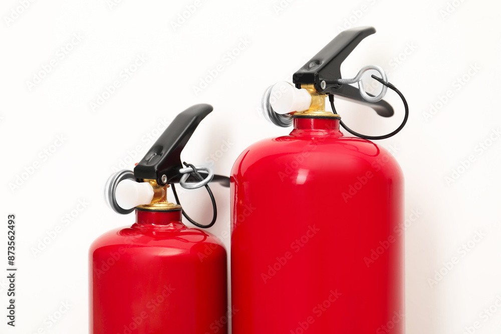 Two fire extinguishers on light background, closeup