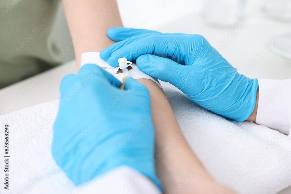 Nurse inserting IV into arm of patient in hospital, closeup Nurse inserting IV into arm of patient in hospital, closeup