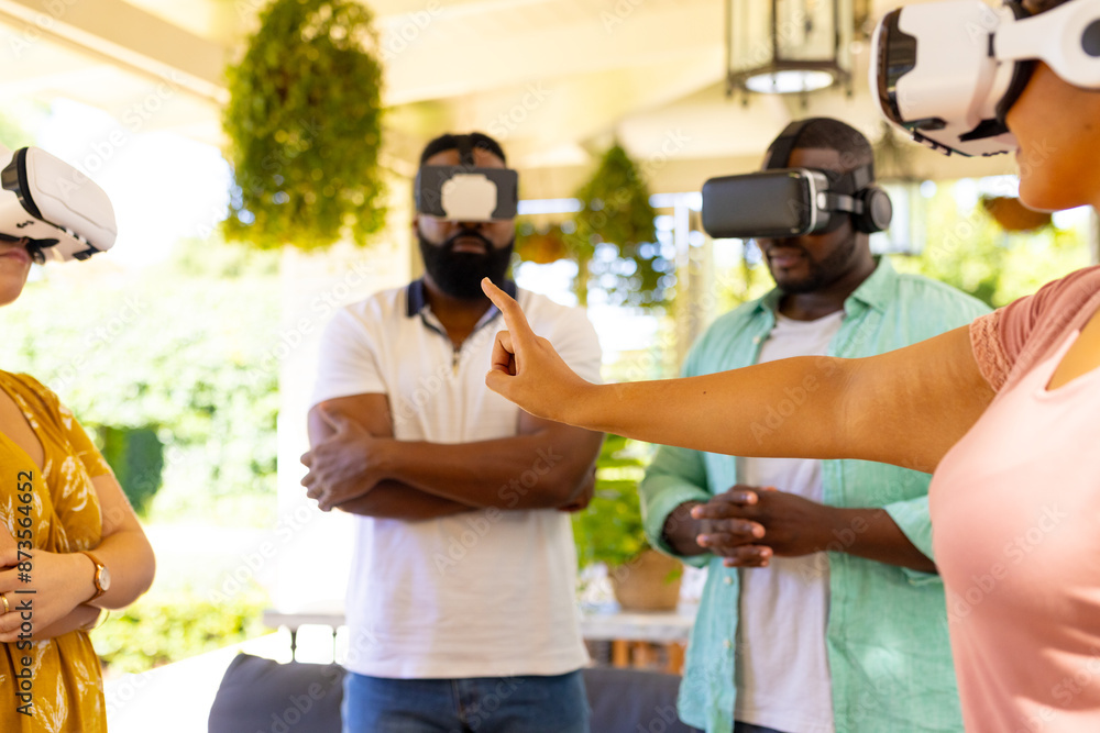 Using VR headsets, group of diverse friends exploring virtual reality together indoors Using VR headsets, group of diverse friends exploring virtual reality together indoors